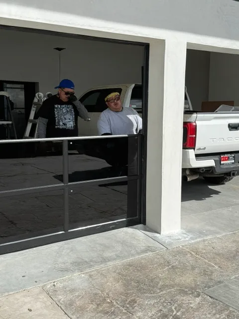 Pros installing a custom glass and steel garage door