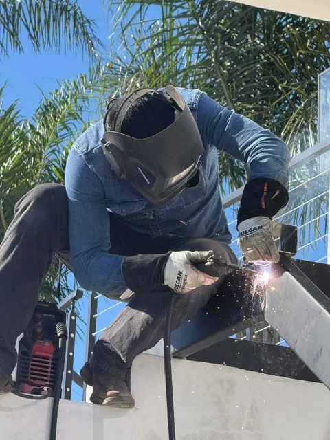 Welder joining structural steel for a railing